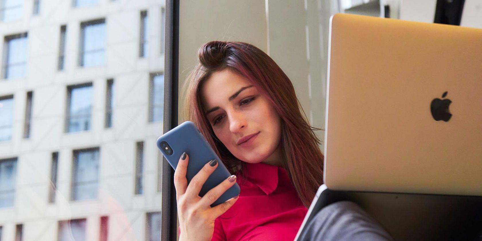 Wanita melihat ponselnya dengan laptop terbuka